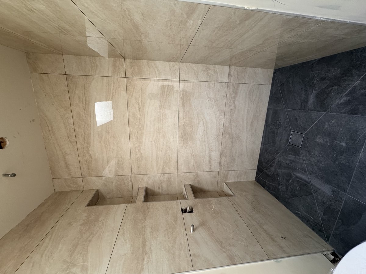 Completed bathroom with travertine and dark marble tile